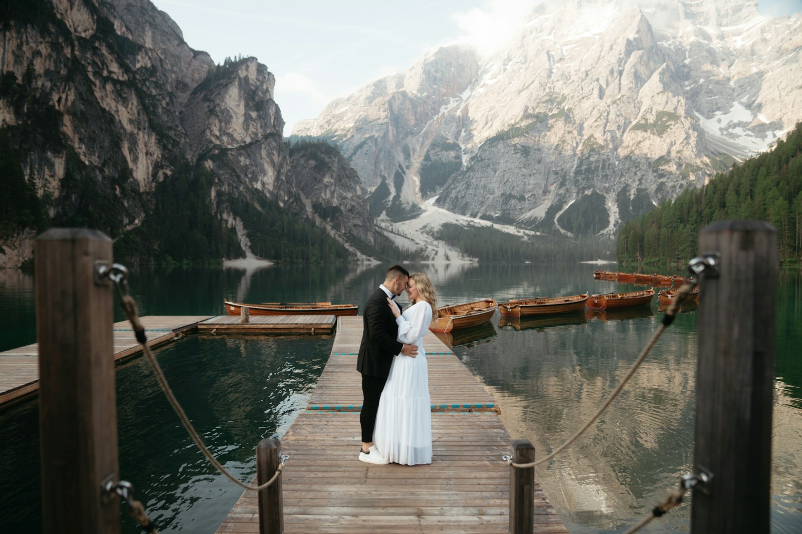 A bride and groom are standing on a dock