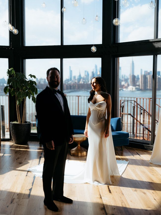 Couple standing at floor-to-ceiling windows framing the New York City skyline at 74Wythe