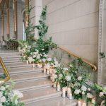 Staircase wrapped in white flowers, greenery and candles at The Admiral Room