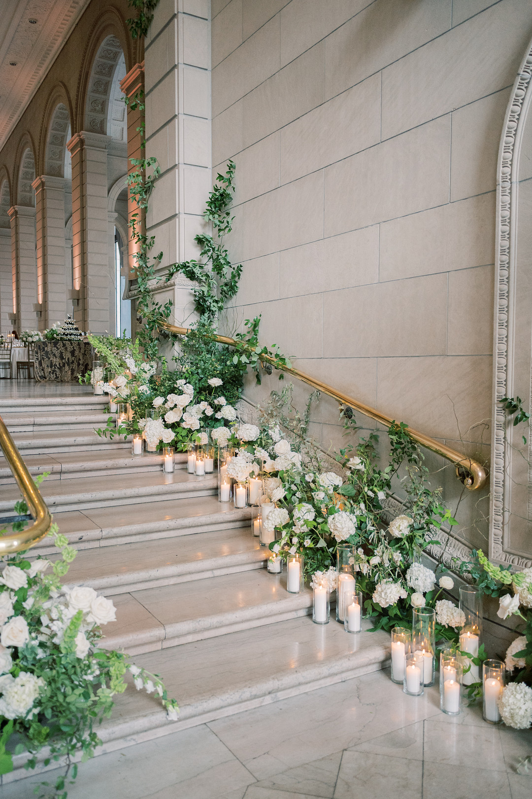 Staircase wrapped in white flowers, greenery and candles at The Admiral Room