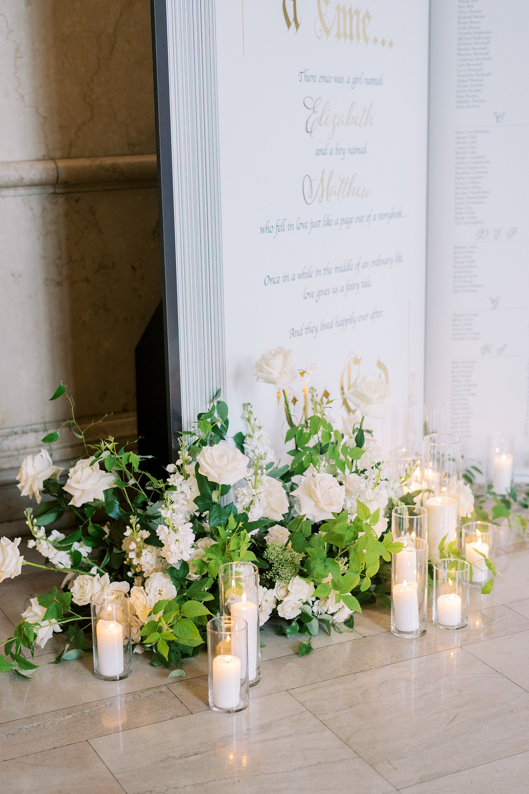 Seating chart sign framed by white flowers and candles