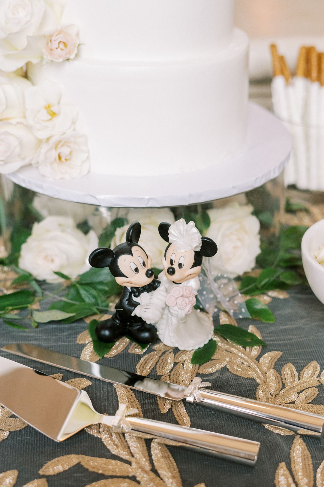 White wedding cake with a bride-and-groom Mickey and Minnie beneath it