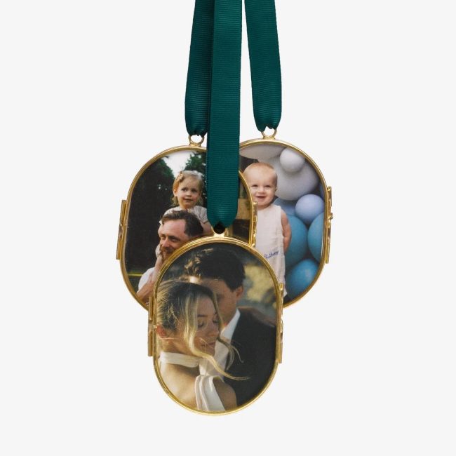 Artifact Uprising brass-framed oval pressed glass ornaments on a green ribbon, the front one holding a couple's photo