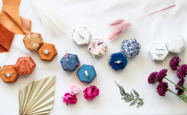 BeatrixAndLuca hexagon ring boxes in printed botanical fabrics, open with rings, among flowers