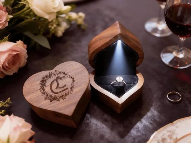 CaskyDesign walnut heart-shaped ring boxes, one engraved with initials and one open and lit with a ring inside