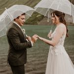 Bride and groom exchanging vows under clear umbrellas in the rain