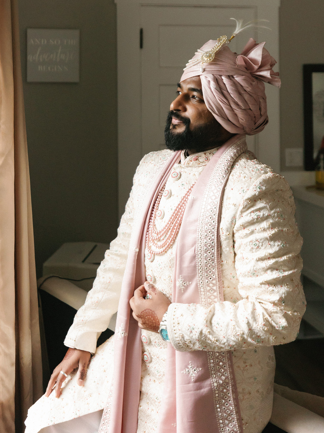 Groom in an ivory sherwani and blush turban getting ready
