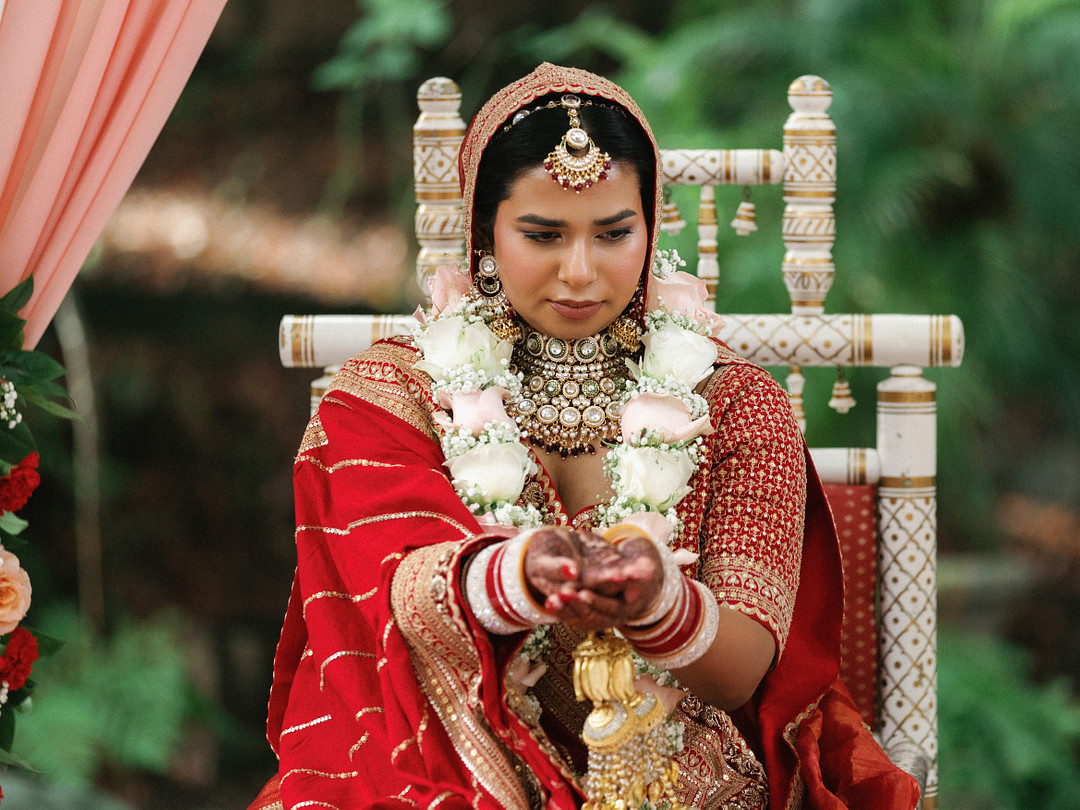 Bride in red bridal attire seated in the mandap
