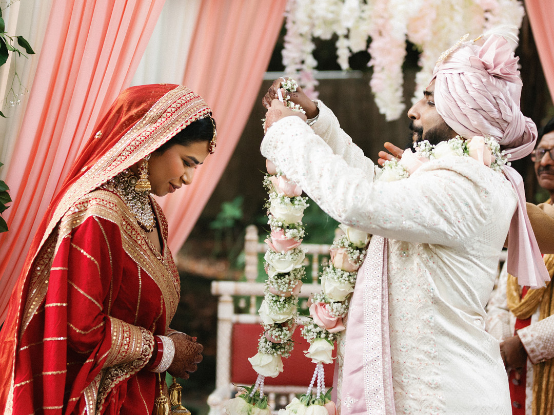 Groom raising a flower garland during the ceremony