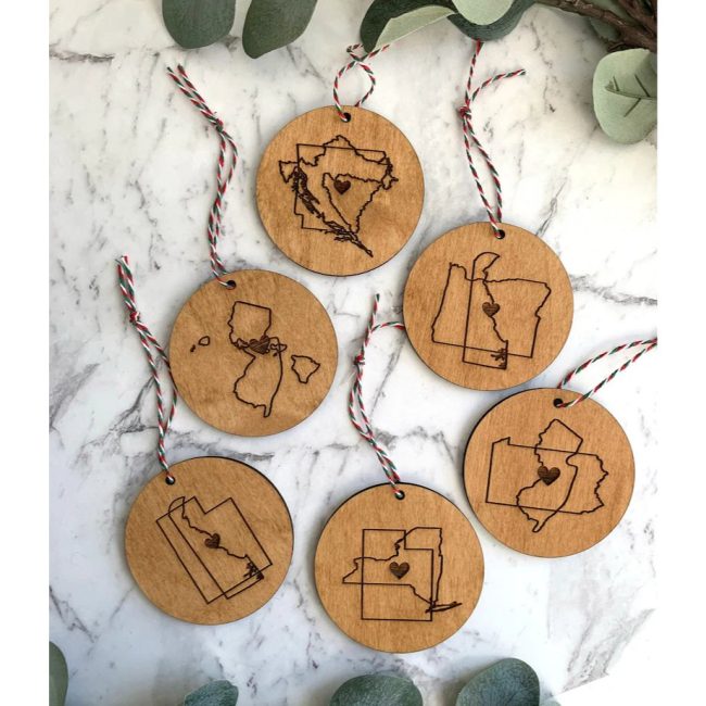 Round wood ornaments engraved with pairs of state outlines joined by a line, each tied with twine