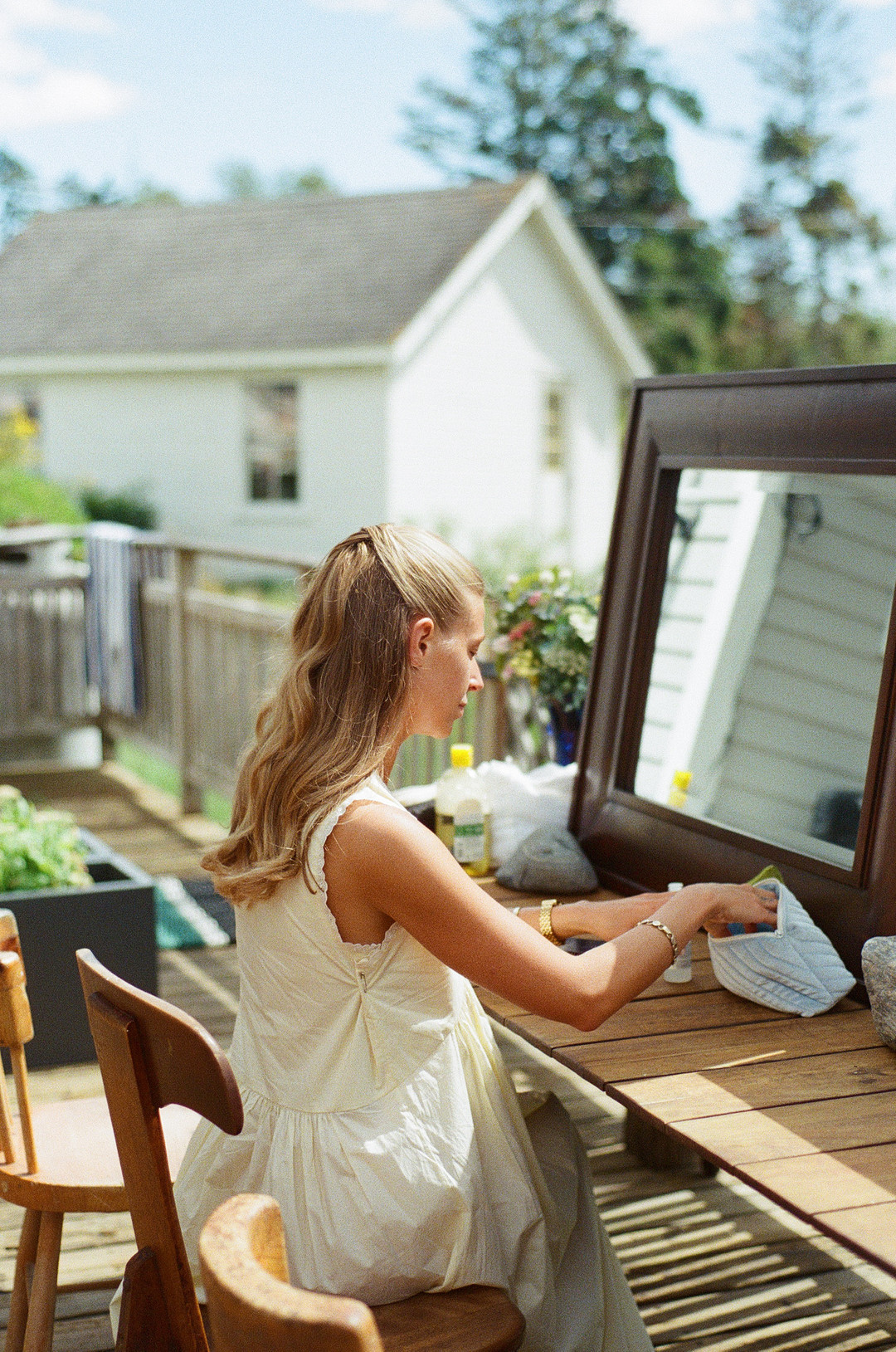 Bride getting ready at a wooden desk on a porch by the water in coastal Maine