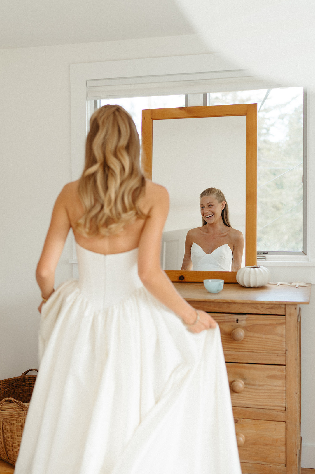Bride in a strapless ballgown checking the mirror before the ceremony