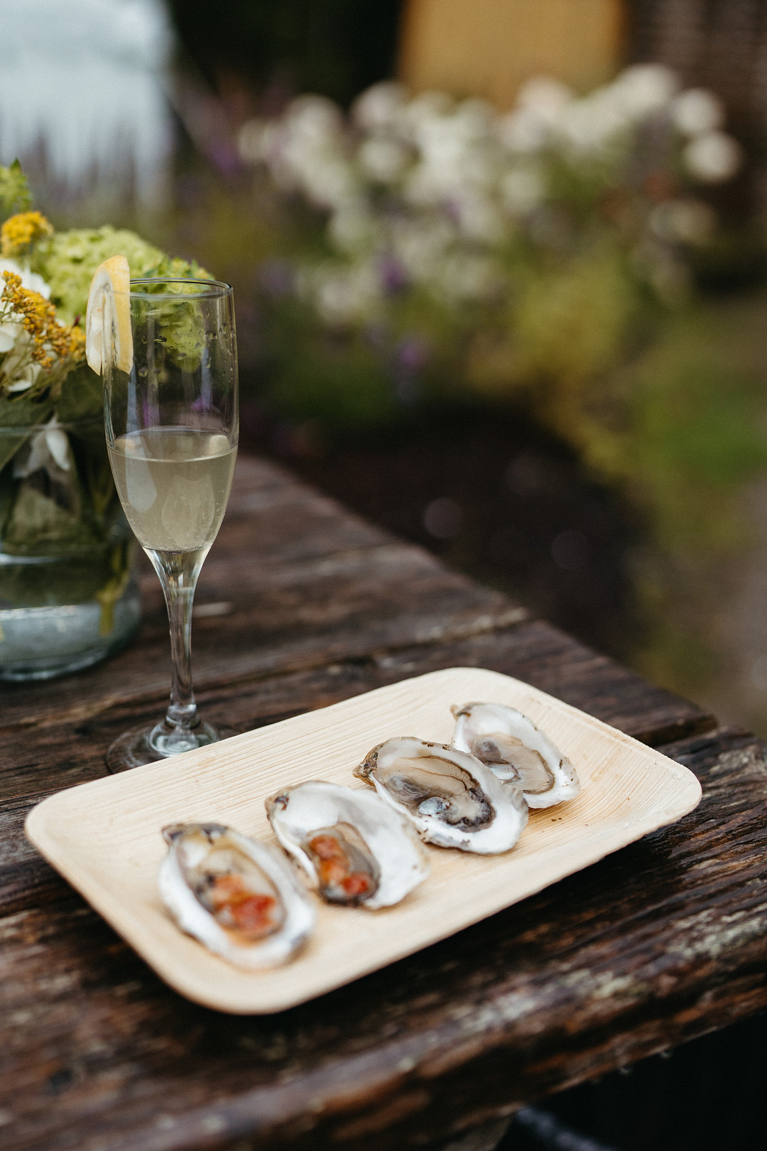 Oysters on a white platter beside a glass of champagne