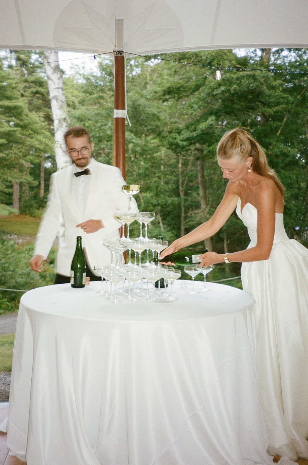 Bride and groom pouring a champagne tower in the tent