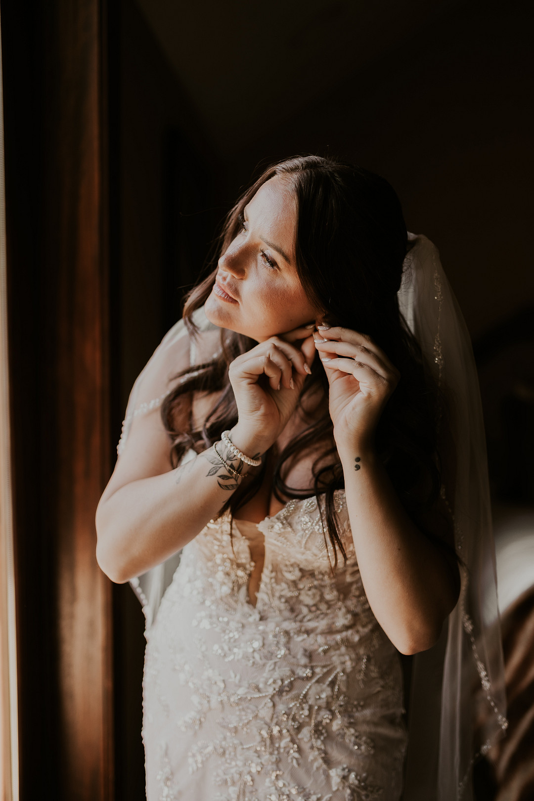 Bride putting on her earrings by the window