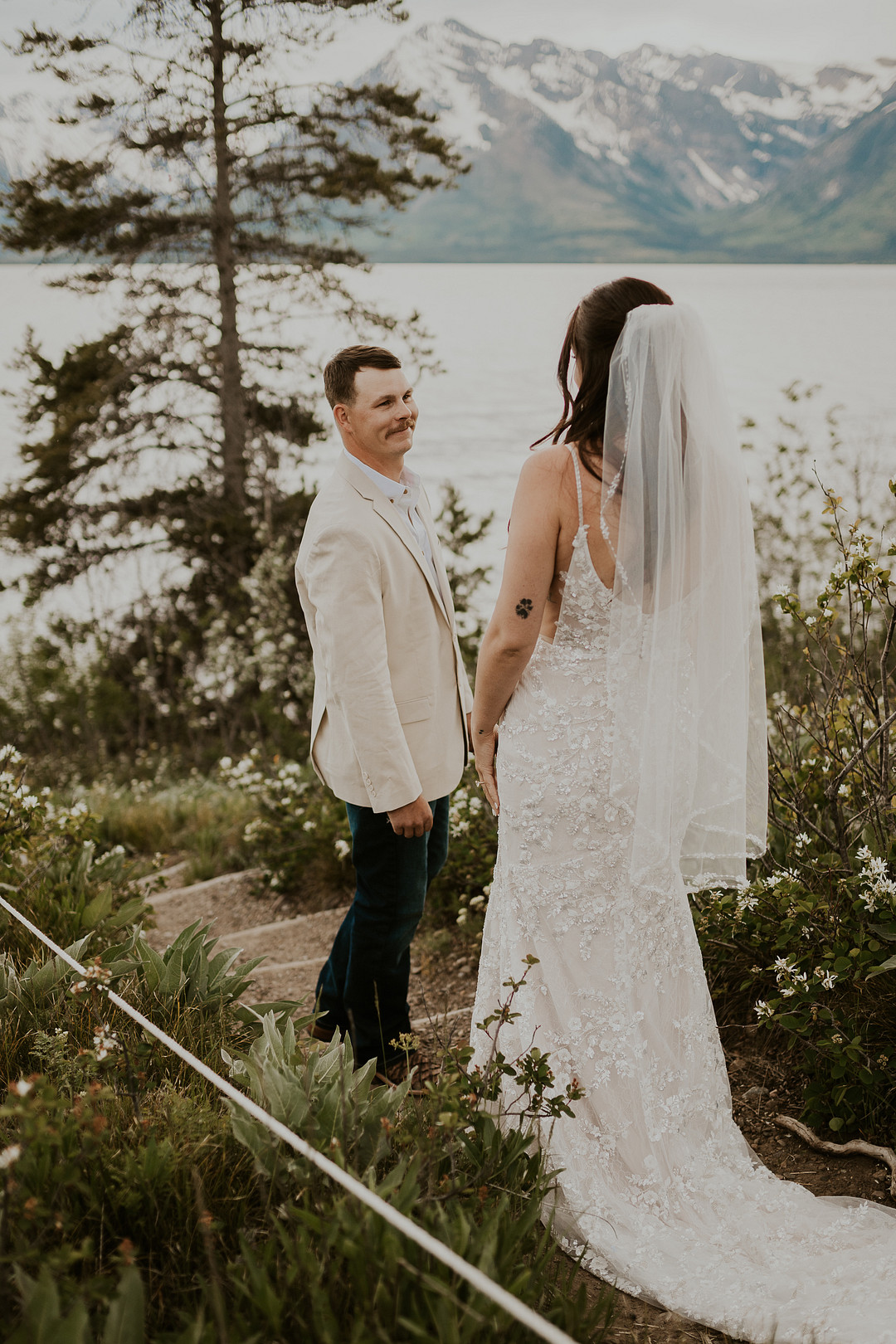 Bride and groom at their first look on the shore of Jackson Lake with the Tetons behind them