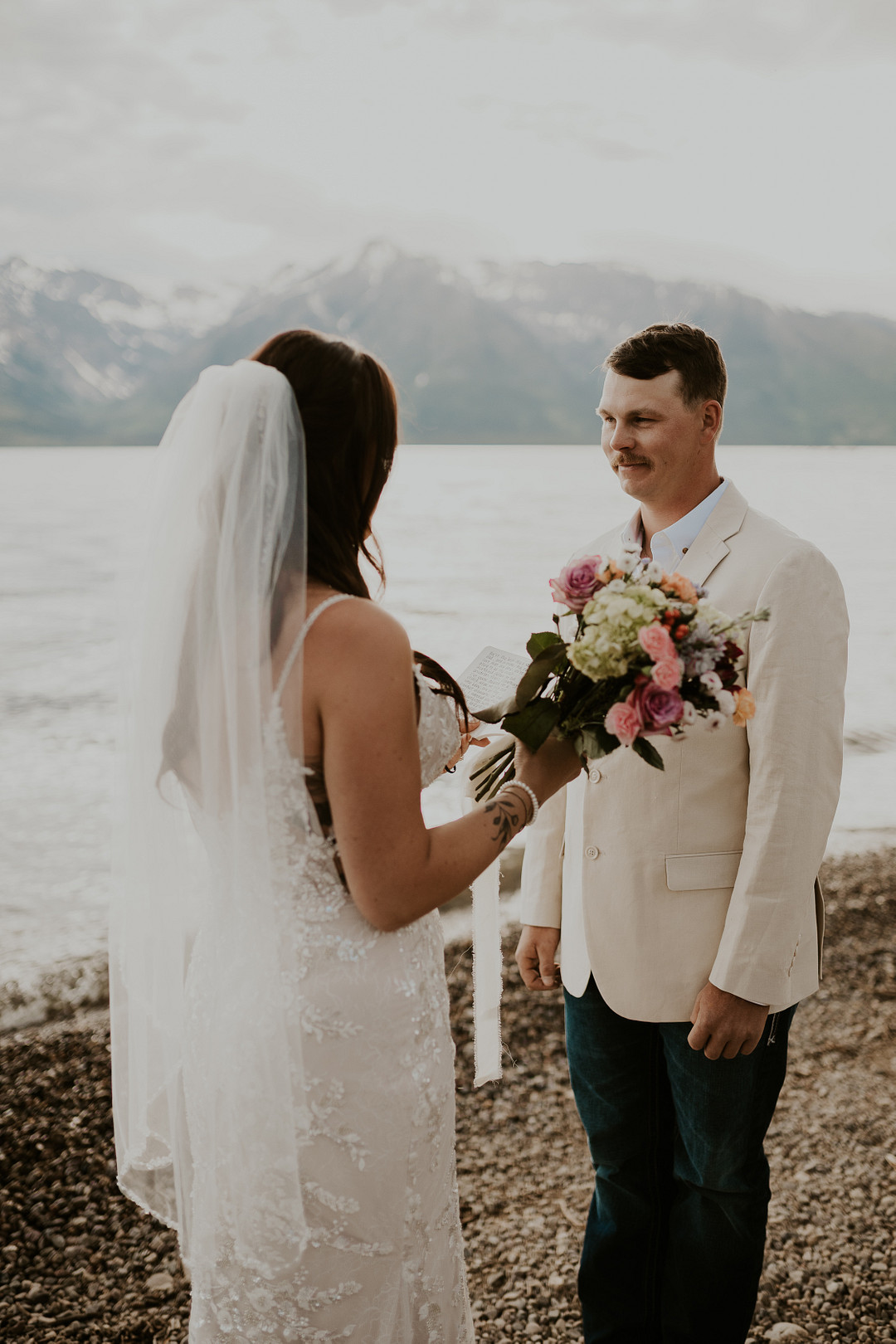 Bride and groom exchanging vows with snowcapped peaks behind them