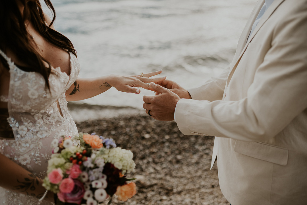 Bride and groom exchanging rings by the lake