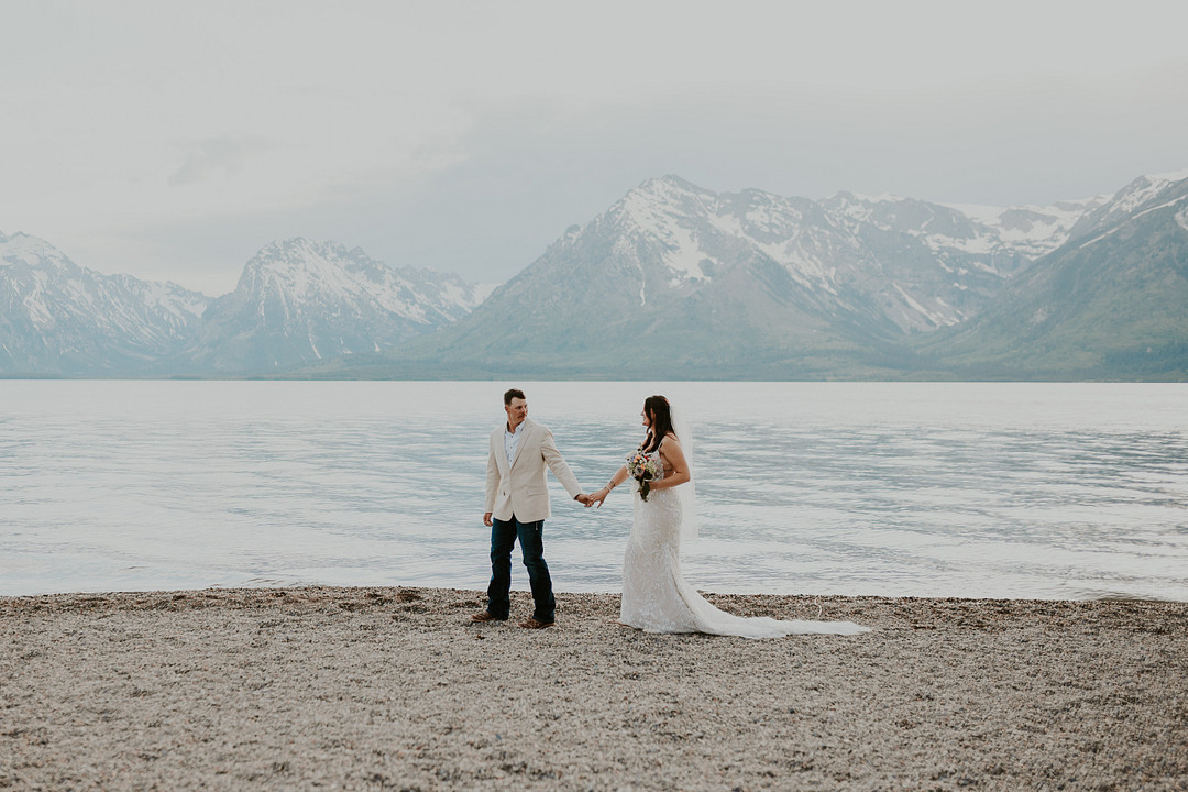 Bride and groom on the shoreline below the Teton Range