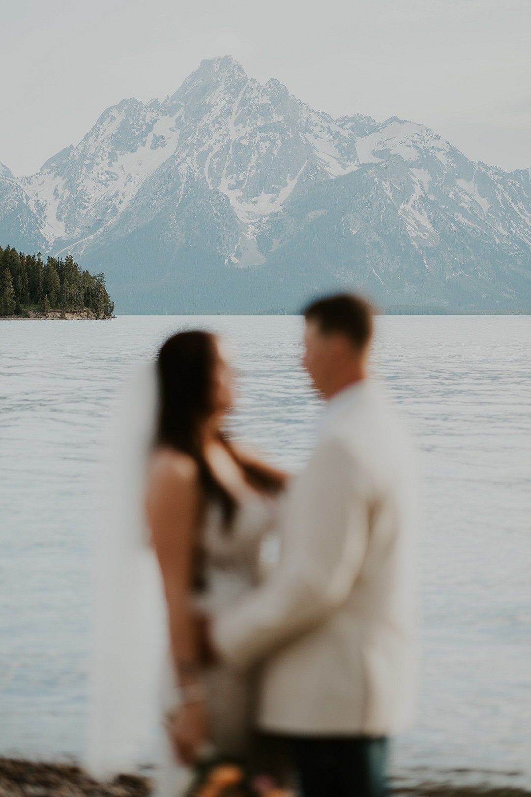 Bride and groom facing each other with a snowcapped peak behind them