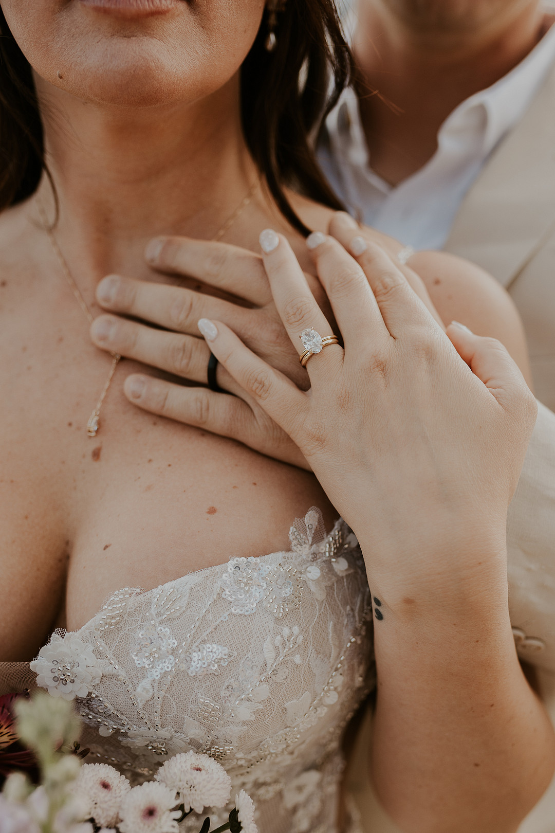 Close-up of the bride's engagement ring and lace bodice