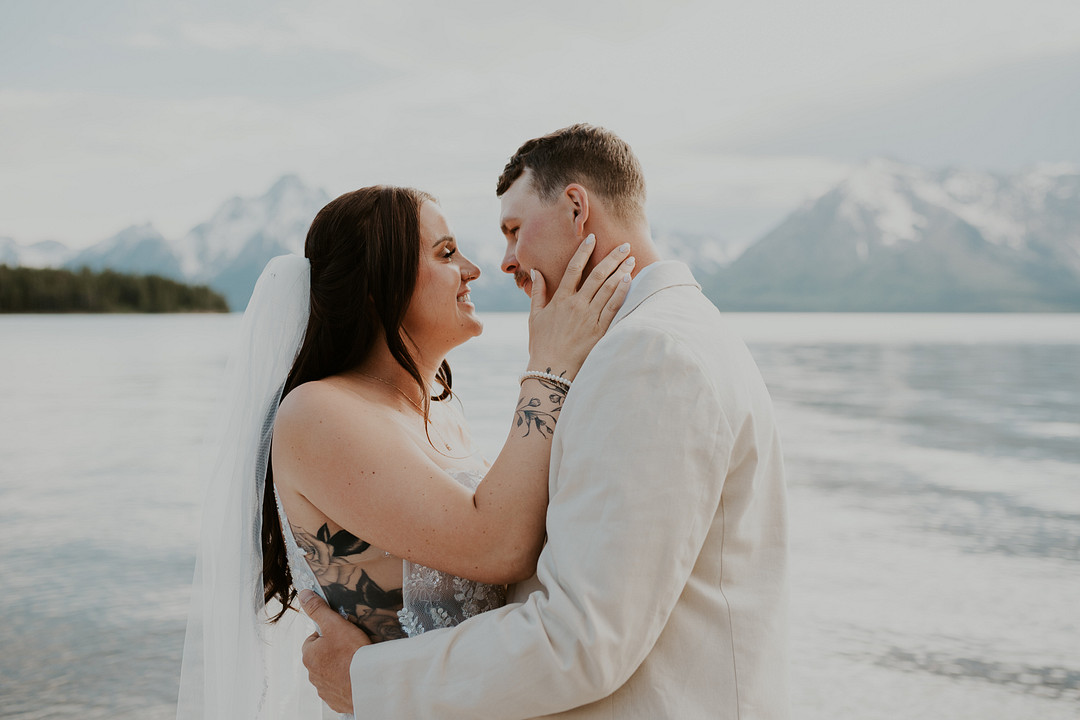 Bride and groom embracing on the shore of Jackson Lake