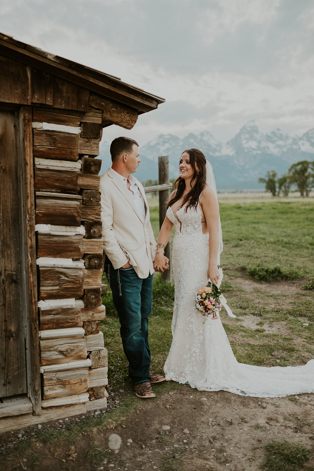 Bride and groom beside a weathered log barn