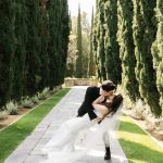 Groom dipping the bride in the cypress-lined walkway
