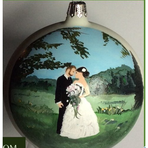 Glass ball ornament hand-painted with a bride and groom kissing in a green field under trees