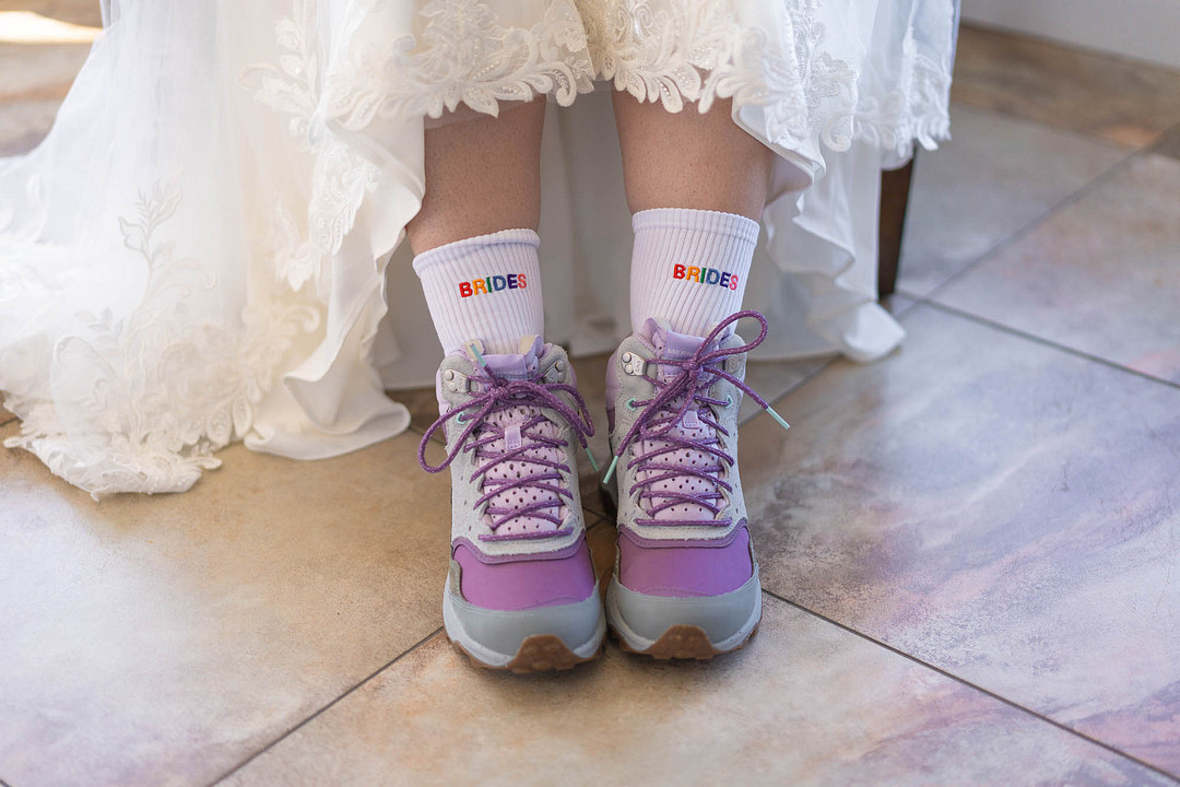 Purple hiking boots peeking out from under a lace wedding gown