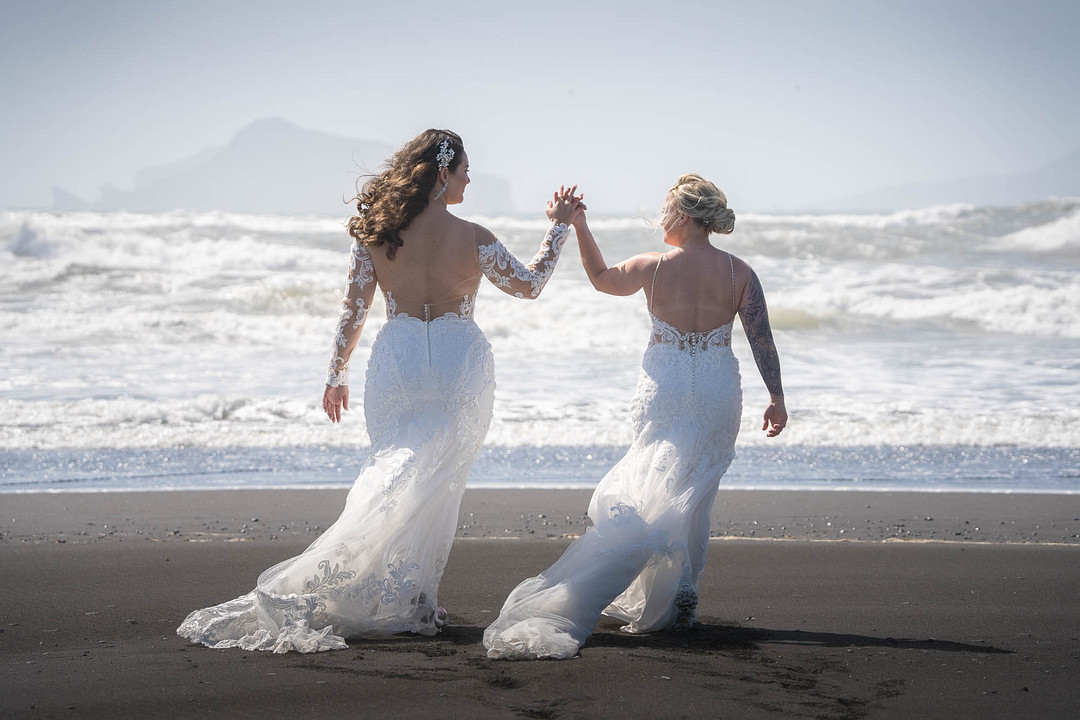 The couple holding hands on a black sand beach in South Iceland