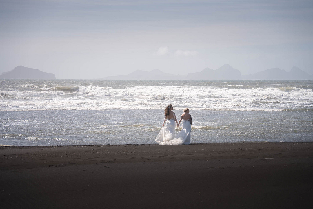 The couple walking along the black sand beach as waves roll in