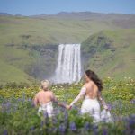 The couple walking through lupines toward a waterfall in Iceland