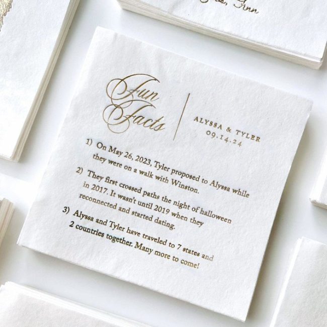 Lavena Creative Co. white cocktail napkins from Minted, foil-printed with Fun Facts about the couple in gold