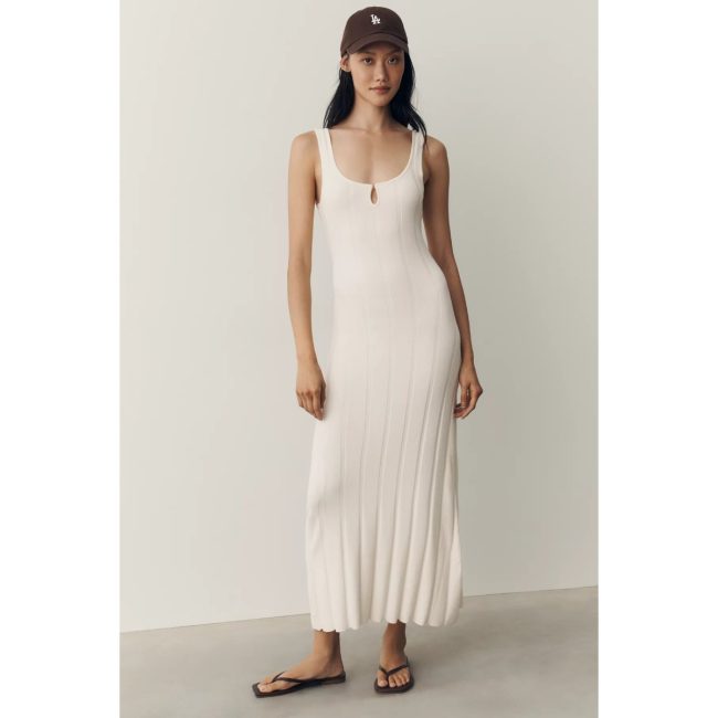 Model in the ivory LSPACE En Route sweater midi dress with a keyhole neckline and a ribbed pleated skirt