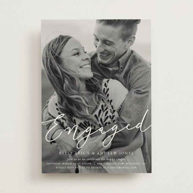 Minted Purest invitation with a full-bleed black-and-white photo of a smiling couple and Engaged in script
