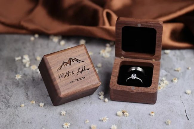 NorthStarEngraving square walnut ring box engraved with names, beside an open box holding two wedding bands