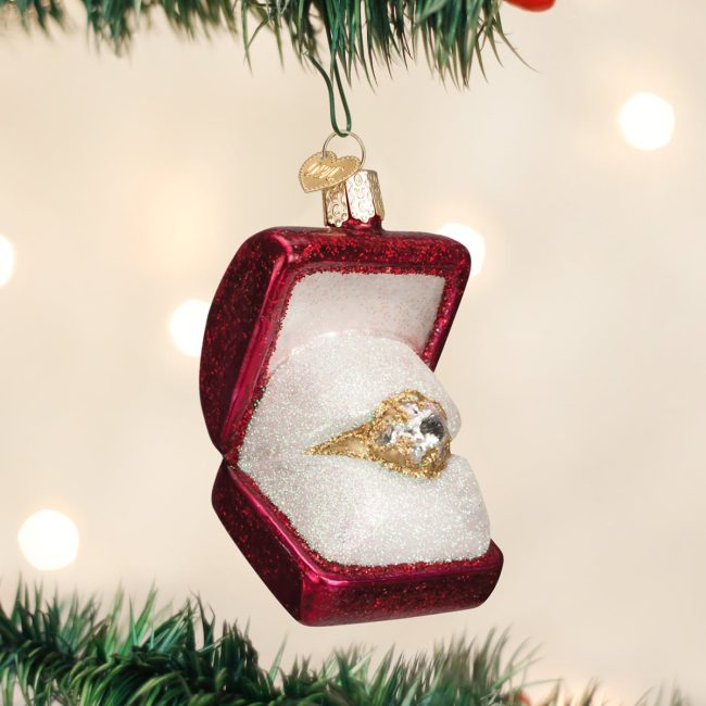 Old World Christmas glass ornament shaped like an open red ring box with a gold diamond ring, hanging on a tree