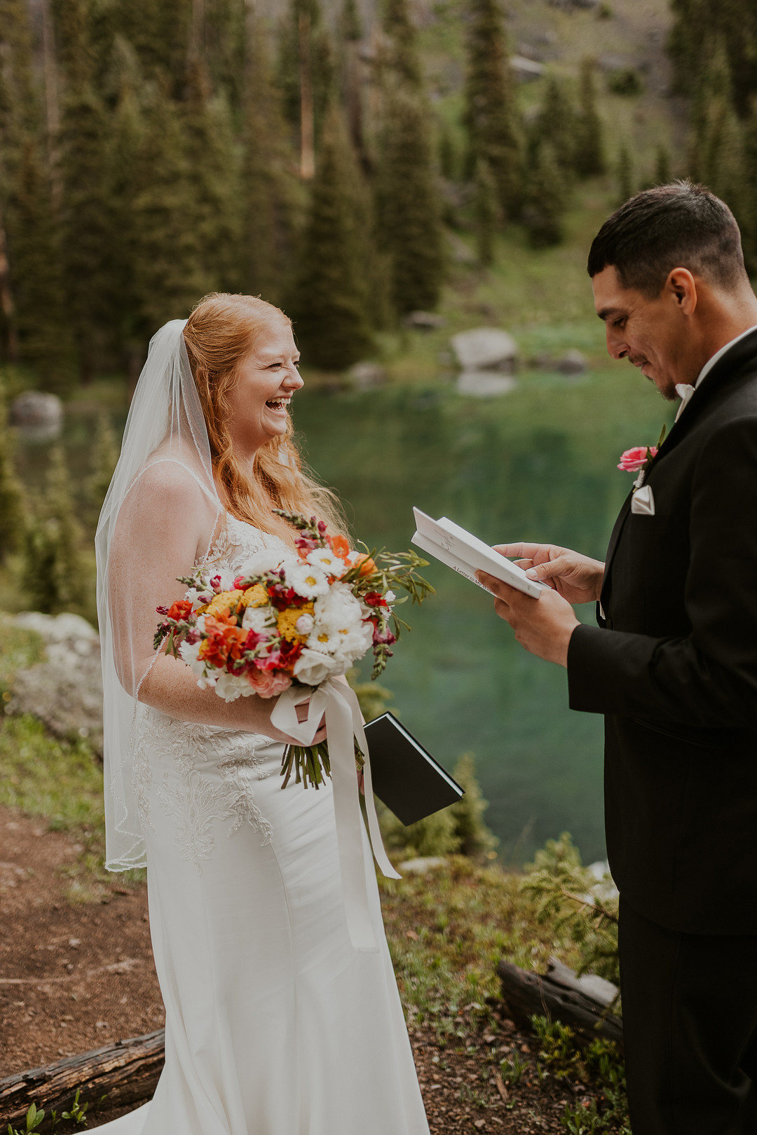 Groom reading his vows to the bride beside the lake