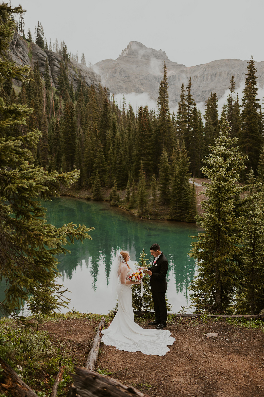 Couple at the edge of the alpine lake with peaks behind them