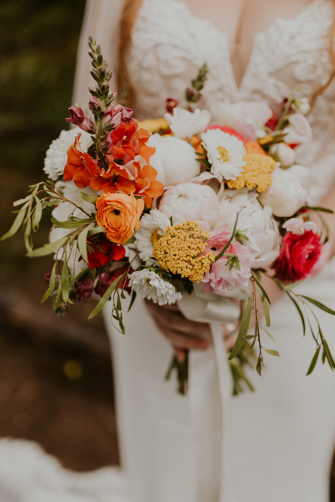 Bride holding a bouquet of orange, red, yellow and white flowers