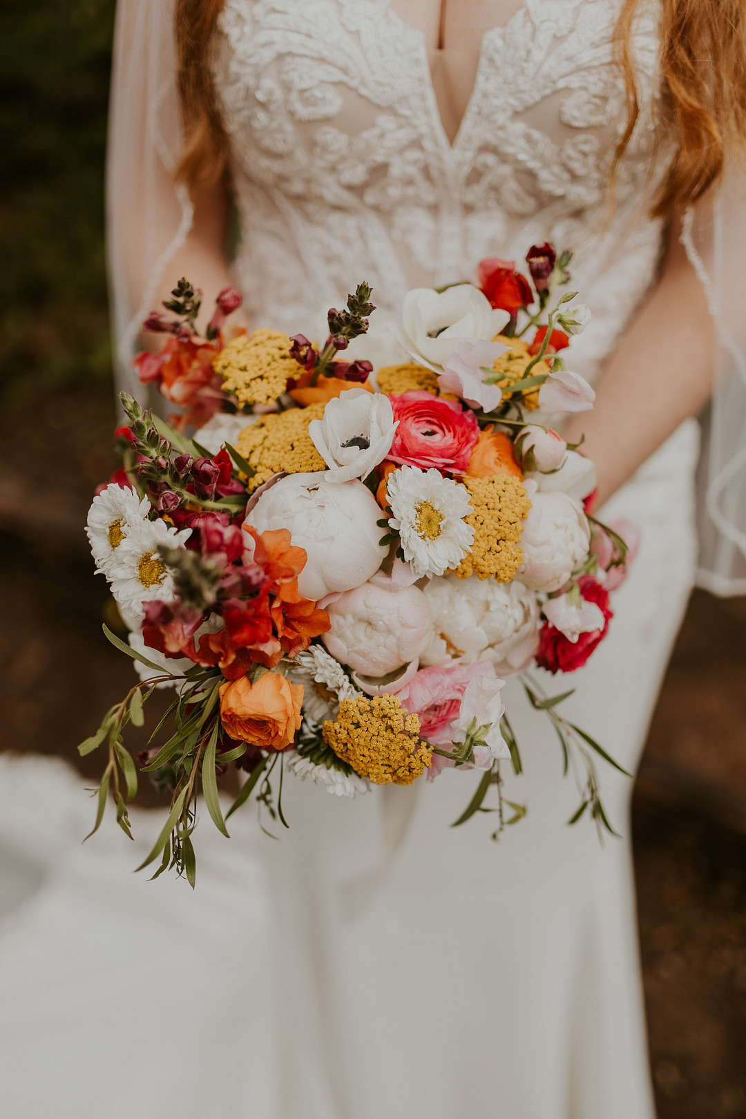 Close-up of the bride's lace bodice and bright bouquet