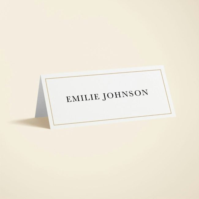 Papier tented ivory place card with a thin gold border and a guest name in black serif letters