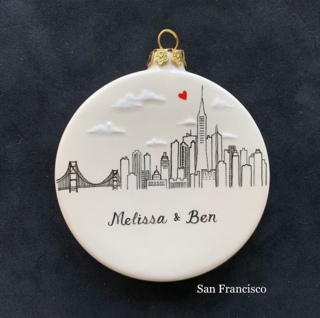 Round ceramic ornament hand-painted with a San Francisco skyline, a small red heart and sample names