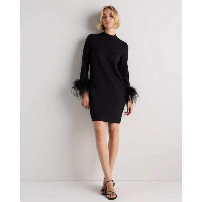 Model in the Quince black ponte mini dress with a mock neck and feather trim at the cuffs