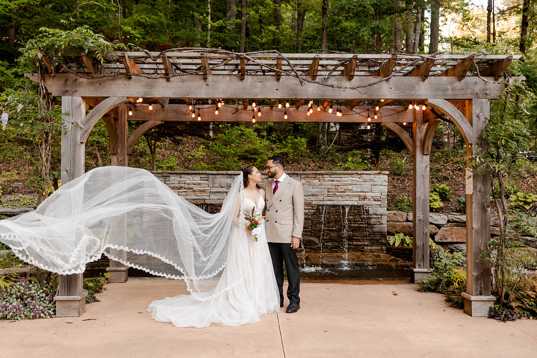Bride's veil floating in the wind under a wooden pergola