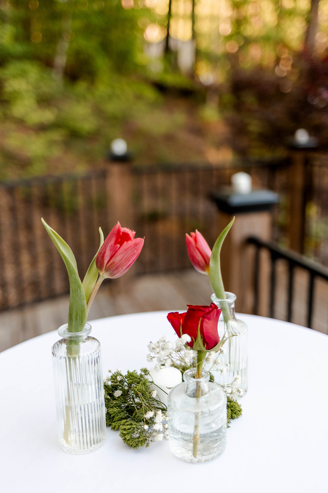 Red tulips in bud vases on a white table