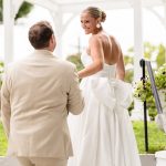 First look under a white pergola at Sea Cliff Manor, the bride's gown finished with a large bow