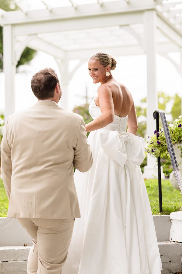 First look under a white pergola at Sea Cliff Manor, the bride's gown finished with a large bow
