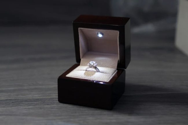 Soulmatebox dark wood ring box with an LED light in the lid shining on a diamond ring